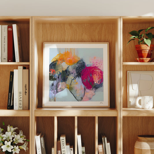 Framed abstract art on a wooden bookshelf with books and decorative items.