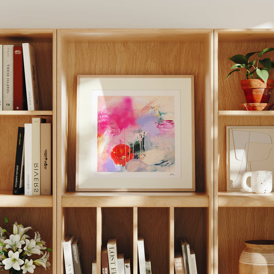 Framed abstract art on a wooden bookshelf with books and decorative items.