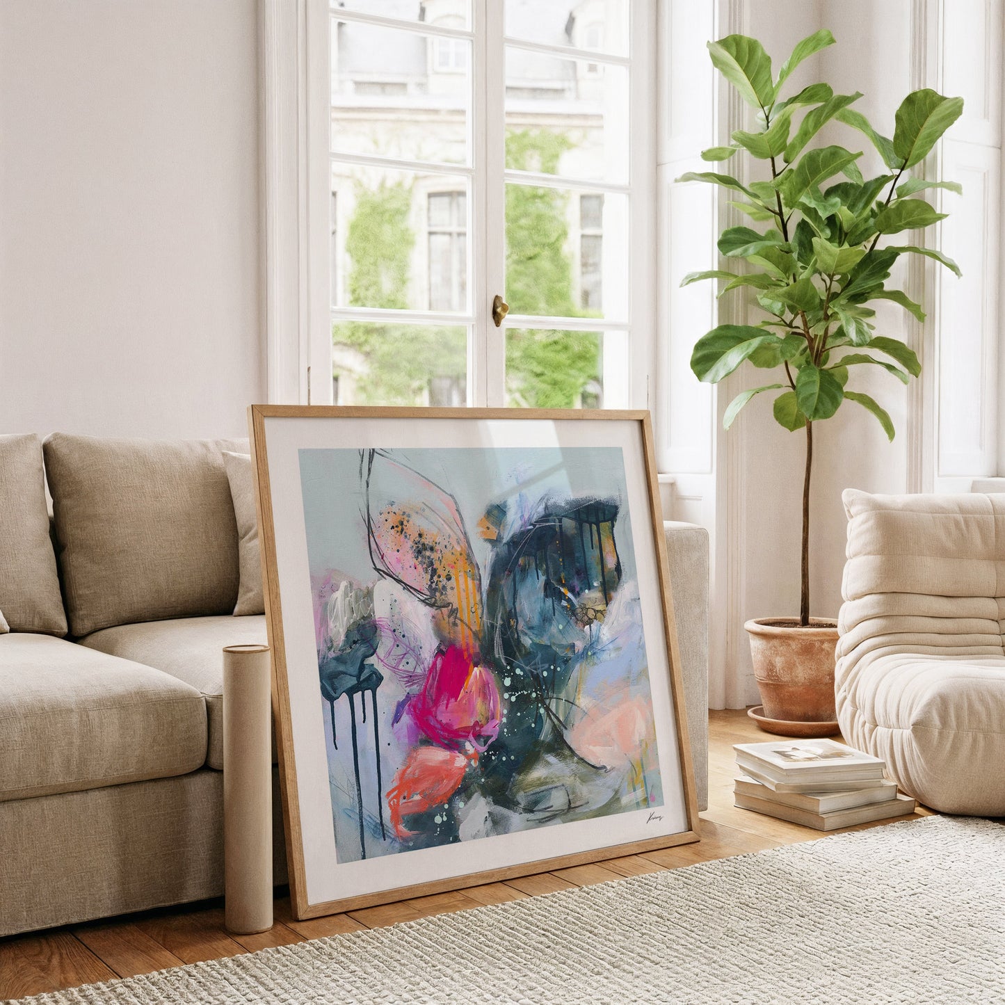 Framed abstract art in a living room with a couch, plant, and books.