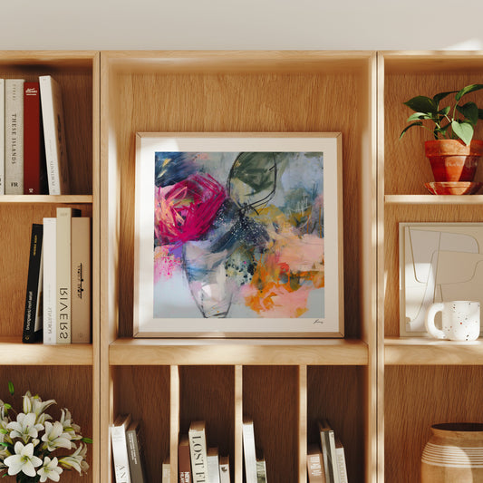 Wooden bookshelf with books, a framed abstract painting, and decorative items.