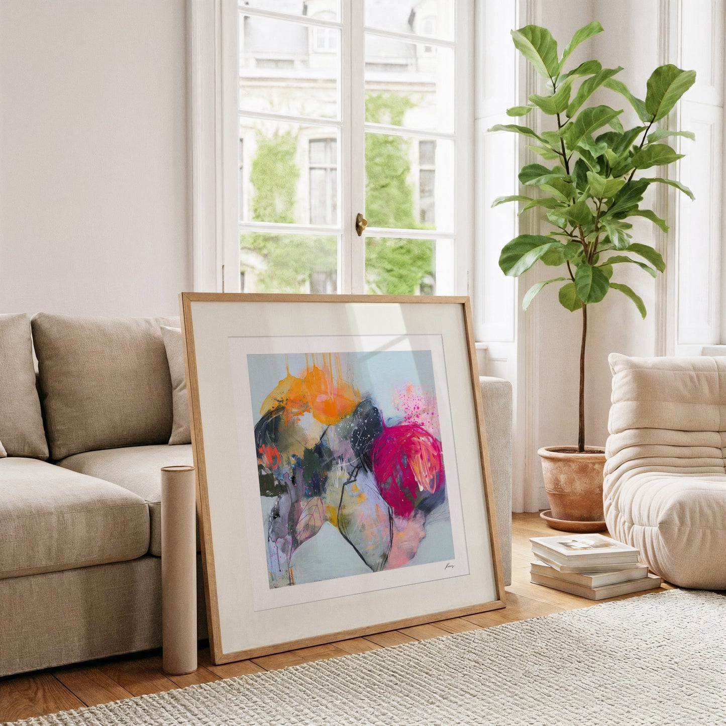 Framed abstract art piece on a coffee table in a living room with a couch and plant.