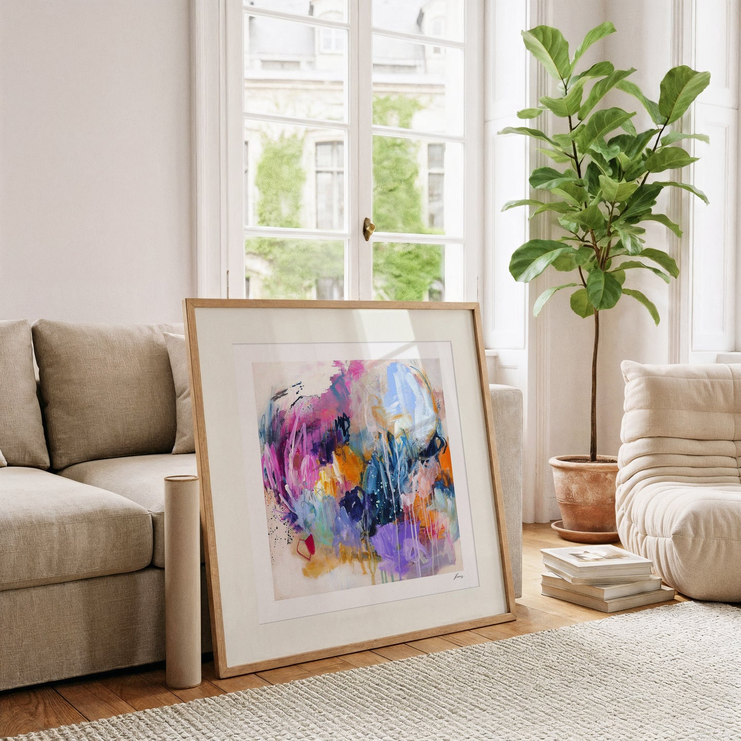 Framed abstract painting in a living room with a couch, plant, and books.