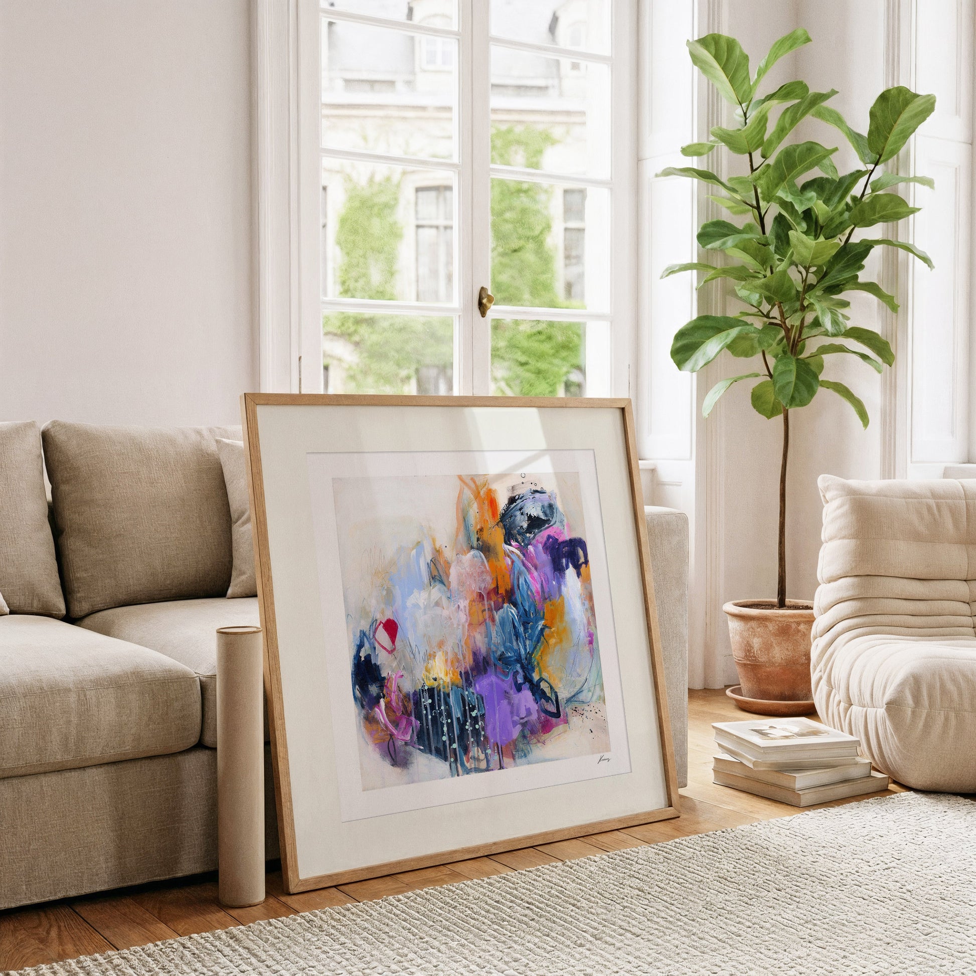 Framed abstract art in a living room with a couch, plant, and books.